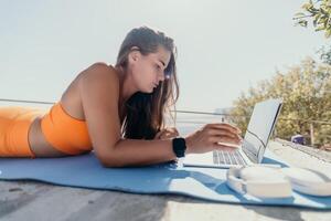 Woman laptop sea. Working remotely on seashore. Happy successful woman female freelancer working on laptop by the sea at sunset, makes a business transaction online. Freelance, remote work on vacation photo