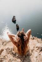 mujer viaje mar. contento turista disfrutar tomando imagen al aire libre para recuerdos. mujer viajero mira a el borde de el acantilado en el mar bahía de montañas, compartiendo viaje aventuras viaje foto