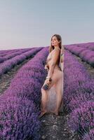 Woman lavender field. Happy carefree woman in beige dress and hat with large brim smelling a blooming lavender on sunset. Perfect for inspirational and warm concepts in travel and wanderlust. Close up photo