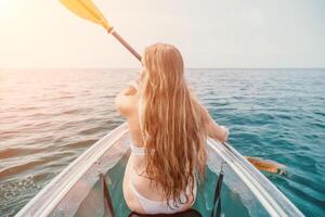 mujer en kayac espalda vista. contento joven mujer con largo pelo flotante en transparente kayac en el cristal claro mar. verano fiesta vacaciones y alegre hembra personas relajante teniendo divertido en el barco foto