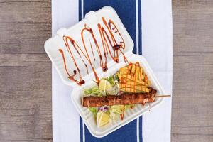 Chicken skewers on a plate with sauces and salad. Table view photo