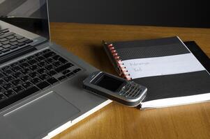 Phone, laptop and empty notebook on the desk photo