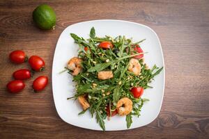 A delicious salad with arugula, cherry tomatoes and shrimps. photo