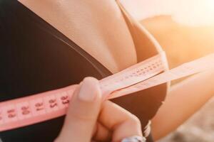 un mujer es participación un rosado cinta medida y es medición su pechos después Mañana aptitud foto