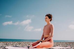 mujer mar pilates deportivo contento medio Envejecido mujer practicando aptitud en playa cerca mar, sonriente activo hembra formación con anillo en yoga estera afuera, disfrutando sano estilo de vida, armonía y meditación foto