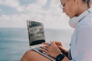 Woman sea laptop. Business woman, freelancer with laptop working over blue sea beach. Happy smiling girl relieves stress from work. Freelance, remote work on vacation, digital nomad, travel concept photo