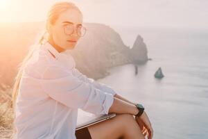 Woman sea laptop. Business woman, freelancer with laptop working over blue sea beach. Happy smiling girl relieves stress from work. Freelance, remote work on vacation, digital nomad, travel concept photo