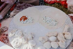 woman's hands making qutab or chebureki with a rolling pin and minced meat onion in dough for culinary concepts related to Azerbaijani, Tatar and Greek cuisine, as well as empanadas in Latin America. photo