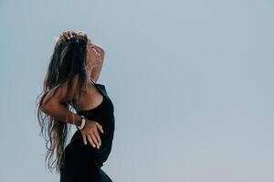 mujer verano viaje mar. contento turista en sombrero disfrutar tomando imagen al aire libre para recuerdos. mujer viajero posando en el playa a mar rodeado por volcánico montañas, compartiendo viaje aventuras viaje foto