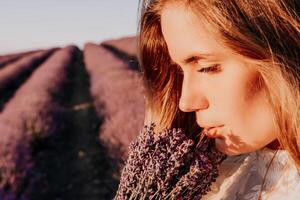 mujer lavanda campo. contento despreocupado mujer en un blanco vestir caminando en un lavanda campo y oliendo un lavanda ramo de flores en puesta de sol. ideal para calentar y inspirador conceptos en pasión de viajar y viajar. foto