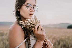 Woman wheat field. Agronomist, Woman farmer check golden ripe barley spikes in cultivated field. A woman is holding a bunch of wheat in her arms. photo