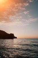 A red burning sunset over the sea with rocky volcanic cliff. Abs photo