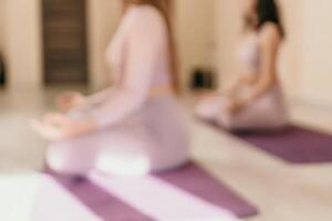 Abstract defocused foto of two young sporty woman, fitness instructor in pink sportswear doing stretching and pilates on yoga mat in the studio with mirror. Female fitness yoga routine concept. photo