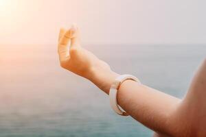 Close up Yoga Hand Gesture of Woman Doing an Outdoor meditation. Blurred sea background. Woman on yoga mat in beach meditation, mental health training or mind wellness by ocean, sea photo