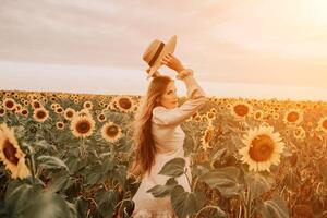 Woman in Sunflower Field. Happy girl in a straw hat posing in a vast field of sunflowers at sunset, enjoy taking picture outdoors for memories. Summer time. photo