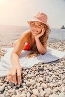 contento joven mujer broncearse o bronceado en un playa playa durante verano vacaciones. sonriente turista en rojo traje de baño disfrutando Dom bronceado acostado en playa cerca a calma claro mar agua. foto