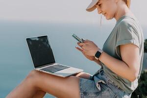 Woman sea laptop. Business woman, freelancer with laptop working over blue sea beach. Happy smiling girl relieves stress from work. Freelance, remote work on vacation, digital nomad, travel concept photo