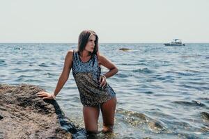 mujer verano viaje mar. contento turista disfrutar tomando imagen al aire libre para recuerdos. mujer viajero posando en el playa a mar rodeado por volcánico montañas, compartiendo viaje aventuras viaje foto