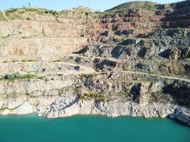 Aerial top view on opencast mining quarry with flooded bottom, turquoise surface of the lake. Quarry pond overgrown with green plants and clear turquoise water photo