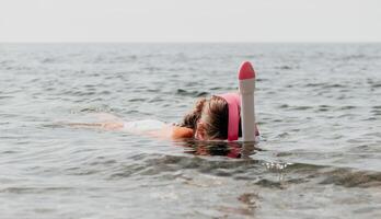 Young happy woman in white bikini and wearing pink mask gets ready for sea snorkeling. Positive smiling woman relaxing and enjoying water activities with family summer travel holidays vacation on sea. photo