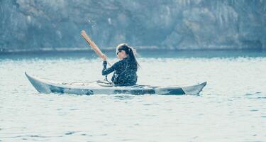 mujer mar kayac. contento sonriente mujer en kayac en océano, remar con de madera remo. calma mar agua y horizonte en antecedentes. activo estilo de vida a mar. verano vacaciones. foto