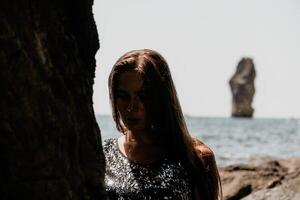 Woman summer travel sea. Happy tourist enjoy taking picture outdoors for memories. Woman traveler posing on the beach at sea surrounded by volcanic mountains, sharing travel adventure journey photo