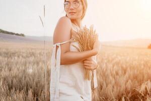 Woman wheat field. Agronomist, Woman farmer check golden ripe barley spikes in cultivated field. A woman is holding a bunch of wheat in her arms. photo