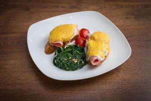 Traditional omelet with vegetables, spinach, tomatoes and herbs on a wooden table. Classic european breakfast. photo