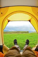 Man lying in tent with a view of mountain photo