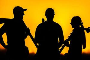 Silhouette of people with guns at sunset photo