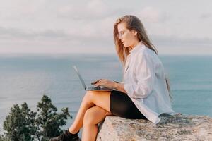 Woman sea laptop. Business woman, freelancer with laptop working over blue sea beach. Happy smiling girl relieves stress from work. Freelance, remote work on vacation, digital nomad, travel concept photo