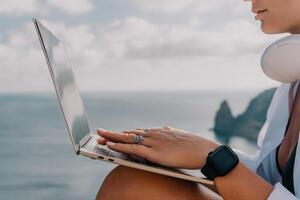 Woman sea laptop. Business woman, freelancer with laptop working over blue sea beach. Happy smiling girl relieves stress from work. Freelance, remote work on vacation, digital nomad, travel concept photo