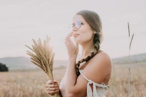 Woman wheat field. Agronomist, Woman farmer check golden ripe barley spikes in cultivated field. A woman is holding a bunch of wheat in her arms. photo