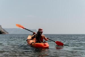 Woman sea kayak. Happy smiling woman paddling in kayak on ocean. Calm sea water and horizon in background. Active lifestyle at sea. Summer vacation. photo