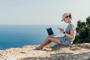 Woman sea laptop. Business woman, freelancer with laptop working over blue sea beach. Happy smiling girl relieves stress from work. Freelance, remote work on vacation, digital nomad, travel concept photo