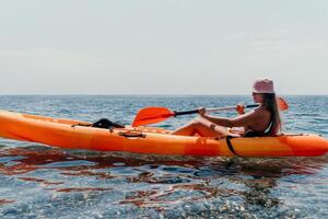 Woman sea kayak. Happy smiling woman paddling in kayak on ocean. Calm sea water and horizon in background. Active lifestyle at sea. Summer vacation. photo