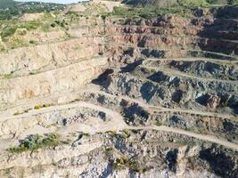 aéreo parte superior ver en a cielo abierto minería cantera con inundado abajo, turquesa superficie de el lago. cantera estanque descuidado con verde plantas y claro turquesa agua foto