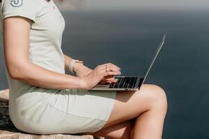 Woman sea laptop. Business woman, freelancer with laptop working over blue sea beach. Happy smiling girl relieves stress from work. Freelance, remote work on vacation, digital nomad, travel concept photo