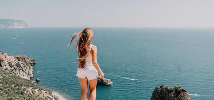 Woman summer travel sea. Happy tourist enjoy taking picture outdoors for memories. Woman traveler posing over sea bay surrounded by volcanic mountains, sharing travel adventure journey photo