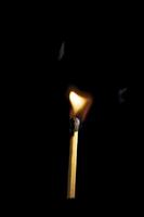 Wooden match burning on a black background photo