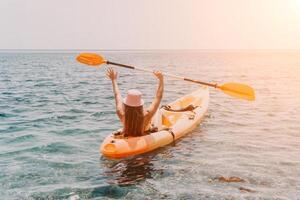 Woman sea kayak. Happy smiling woman paddling in kayak on ocean. Calm sea water and horizon in background. Active lifestyle at sea. Summer vacation. photo