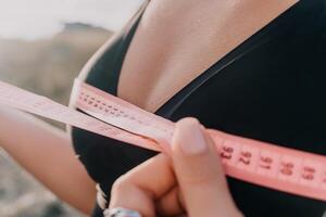 A woman is holding a pink tape measure and is measuring her breasts after morning fitness photo