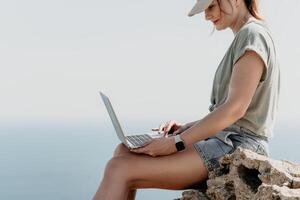 Woman sea laptop. Business woman, freelancer with laptop working over blue sea beach. Happy smiling girl relieves stress from work. Freelance, remote work on vacation, digital nomad, travel concept photo