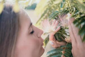 belleza retrato de contento mujer de cerca. joven niña oliendo chino acacia rosado cierne flores retrato de joven mujer en floreciente primavera, verano jardín. romántico onda. hembra y naturaleza foto