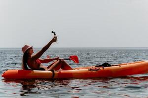 Woman sea kayak. Happy smiling woman paddling in kayak on ocean. Calm sea water and horizon in background. Active lifestyle at sea. Summer vacation. photo