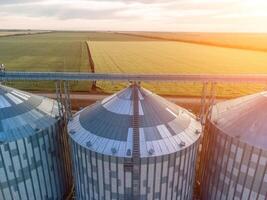 Modern metal silos on agro-processing and manufacturing plant. Aerial view of Granary elevator processing drying cleaning and storage of agricultural products, flour, cereals and grain. Nobody. photo