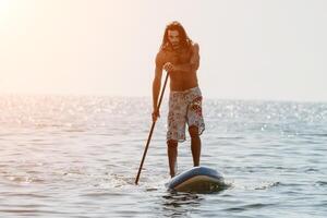 hombre cenar mar. fuerte atlético hombre aprende a paleta cenar en pie en tablero en abierto mar Oceano en soleado día. verano fiesta vacaciones y viaje concepto. aéreo vista. lento movimiento foto