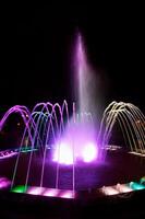 Colored water fountain at night photo