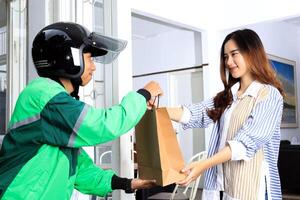 Delivery Online Driver Courier with Helmet and Uniform Sending Package to Female Customer photo