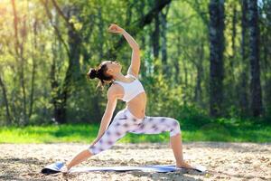 Young woman doing yoga exercises in the summer city park. Health lifestyle concept. photo